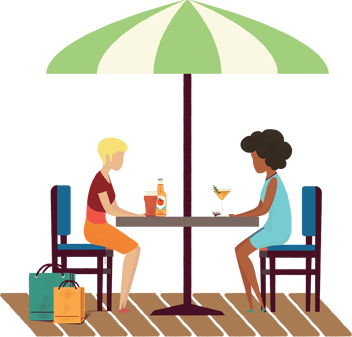 Two women sitting at a table in front of a tent.