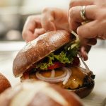 a person cutting a sandwich with a knife.