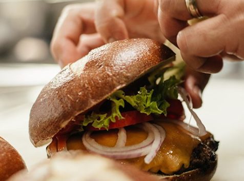 a person cutting a sandwich with a knife.