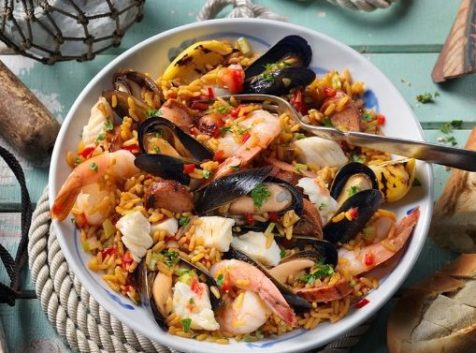 a bowl of seafood and rice on a table.