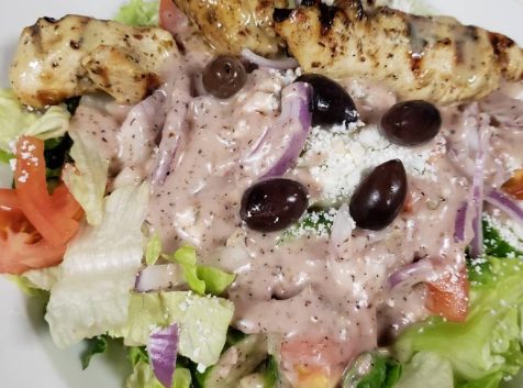 a white plate topped with a salad and chicken.