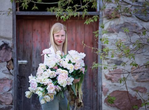 a woman holding a bouquet of flowers in front of a door.