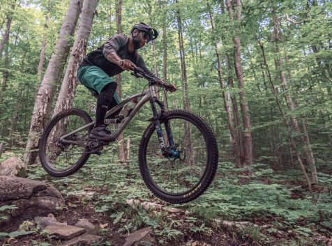 a man riding a mountain bike through a forest.