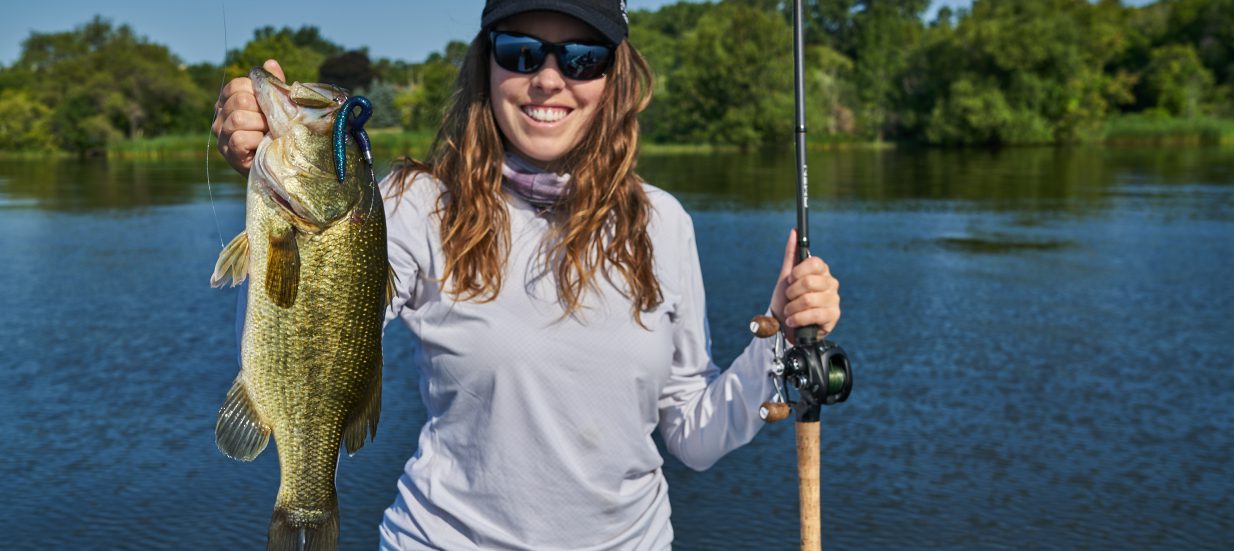 a woman holding a fish while standing on a boat.
