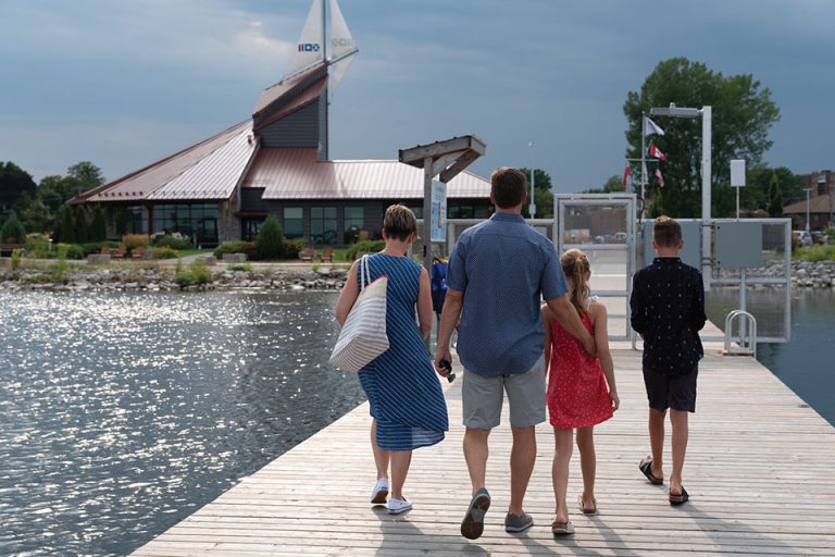 a group of people walking along a pier next to a body of water.