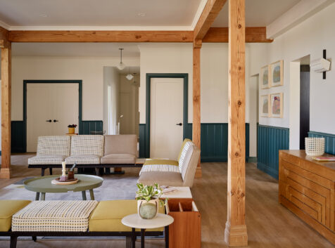 a modern living room with muted tones, hardwood floors and wood beams