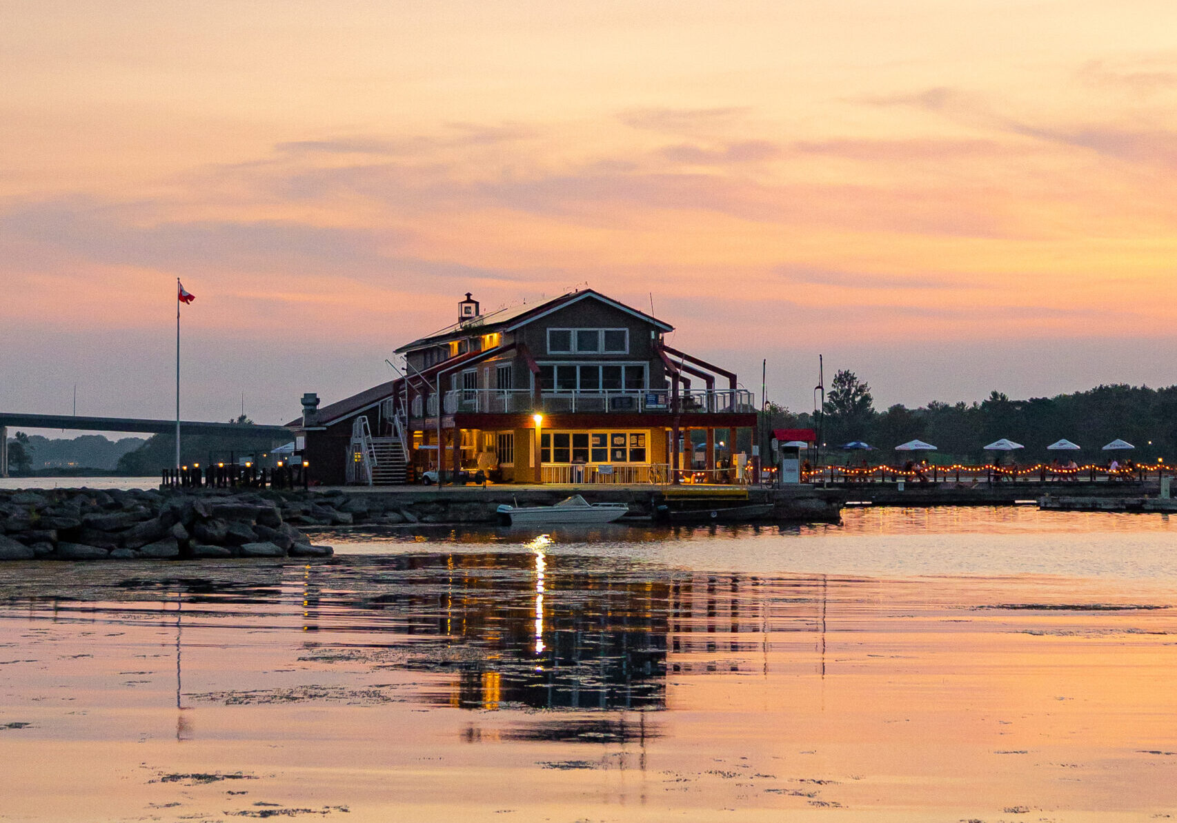 a marina light up with a warm sunset sky in the background and water in the foreground