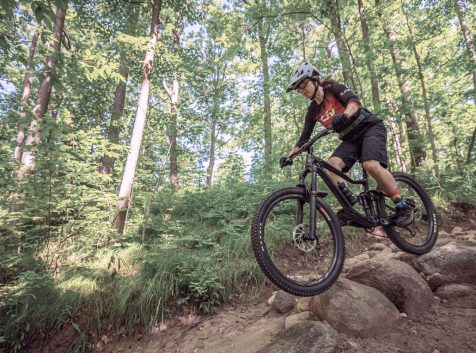 a person riding a bike on a trail in the woods.