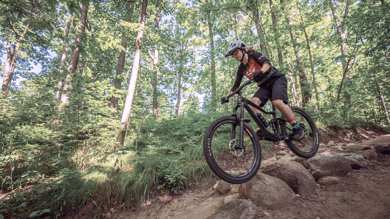 a person riding a bike on a trail in the woods.