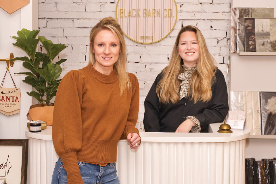 two women standing behind a counter in a store.