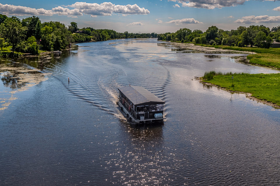 a boat traveling down a river next to a lush green field.
