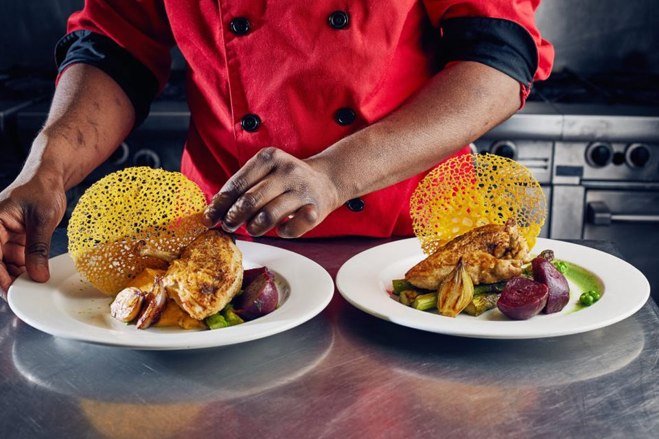 a chef is decorating a plate of food.