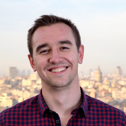 a man smiling in front of a cityscape.