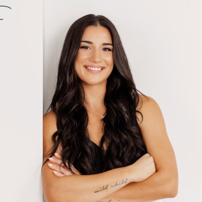 a woman with her arms crossed leaning against a wall.