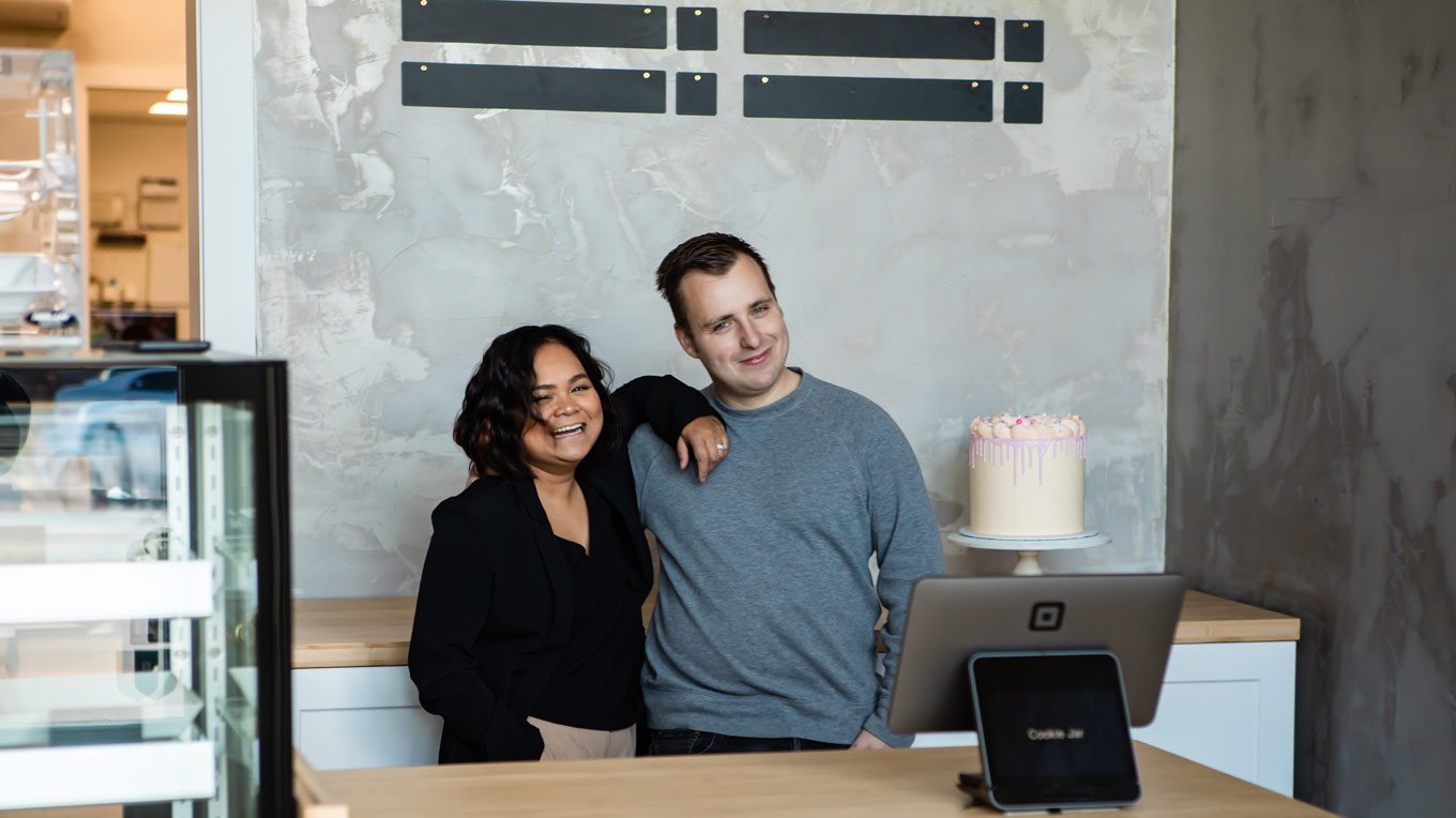 a man and a woman standing in front of a cake.