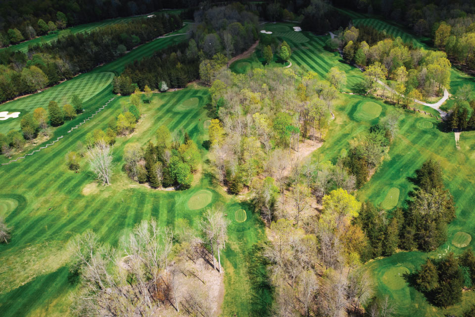 an aerial view of a golf course surrounded by trees.