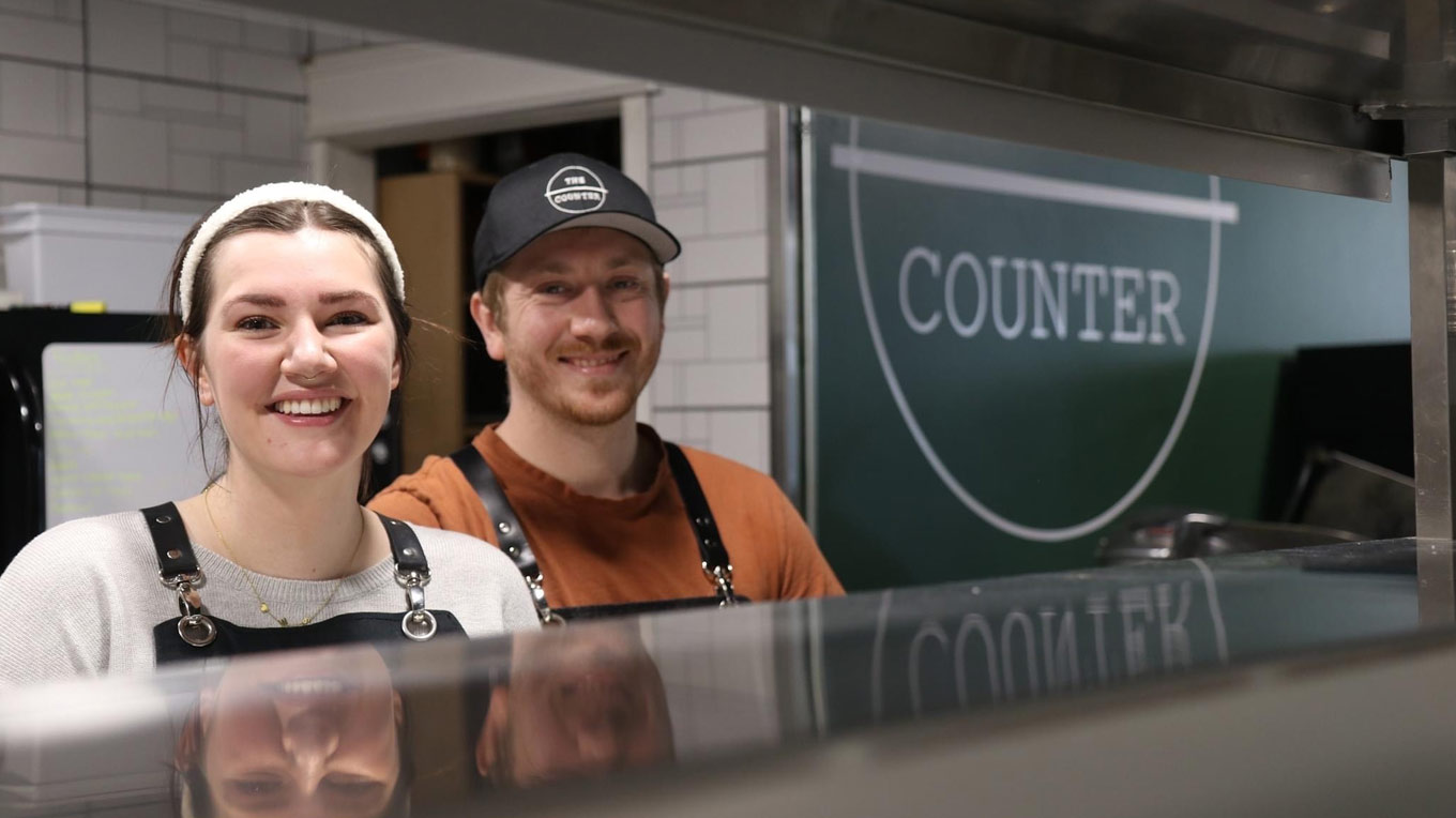 a man and a woman standing in front of a counter.