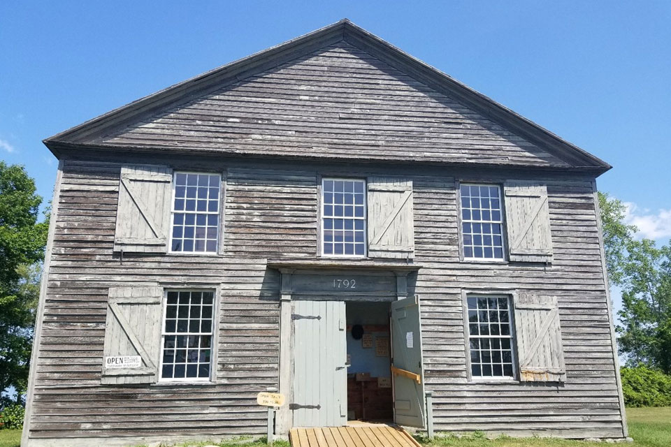 an old wooden building with two windows and a door.
