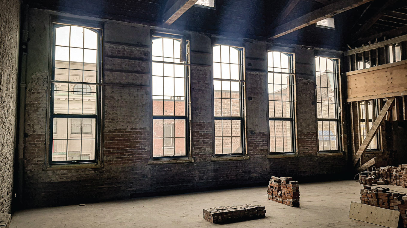 a large room with three windows and a bench.