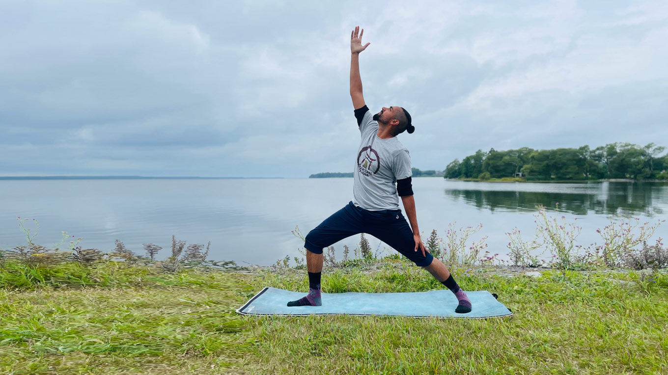 a woman doing yoga on a mat near the water.