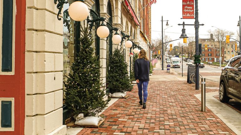 a woman walking down a brick sidewalk next to a car.