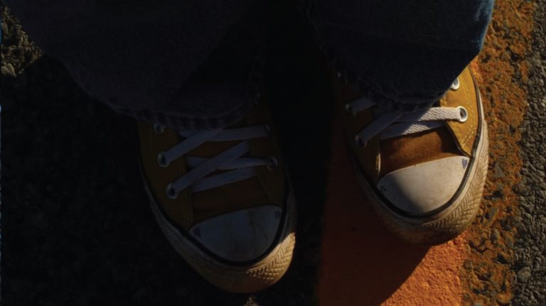 a person standing on a sidewalk with their shoes on.