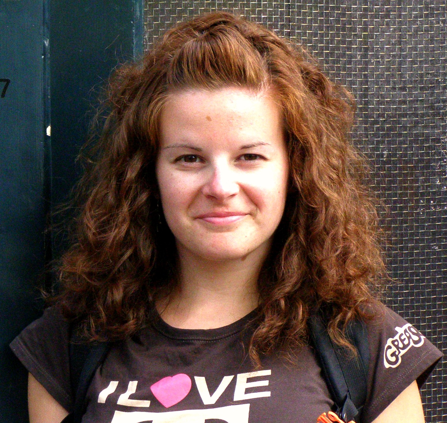 A woman wearing a tee shirt and carrying a backpack.