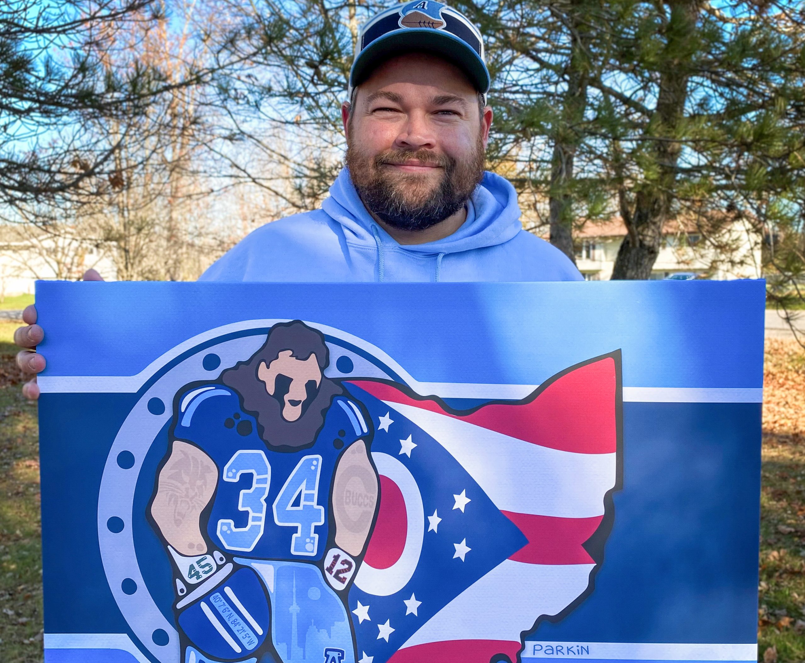 man holding up a painting of a football player
