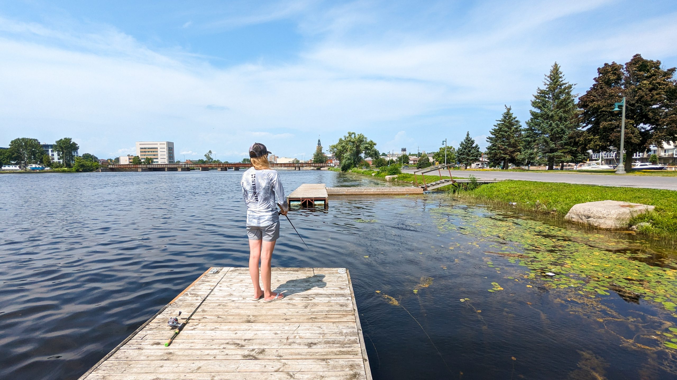 woman standing on a dock fishing by the shore