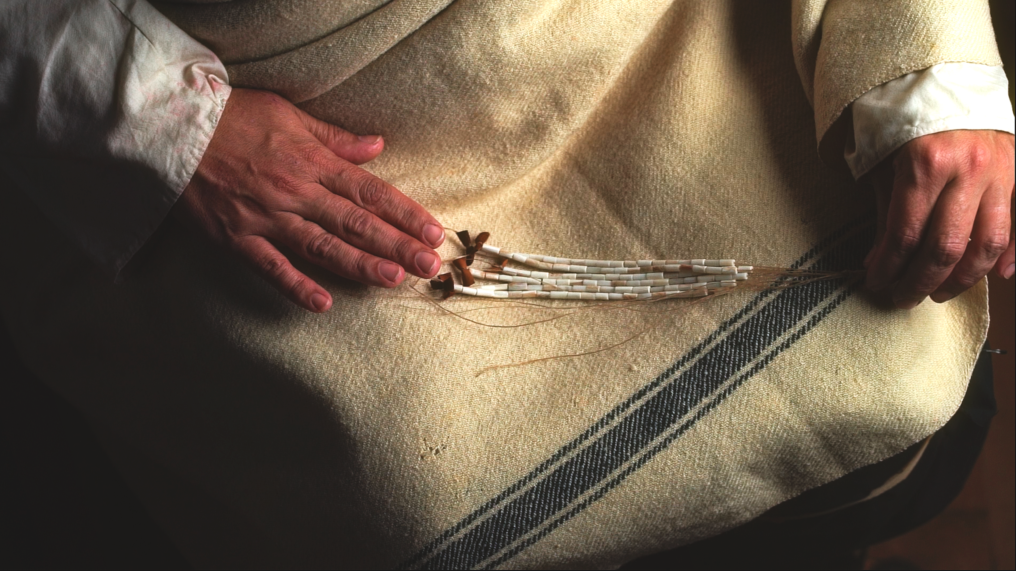 a person's lap wth strings of beaded wampum in their hands