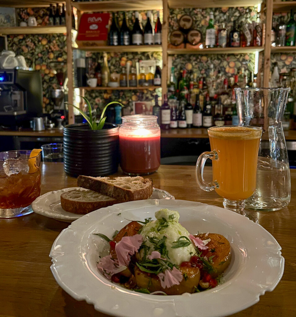 burrata and beverages sitting on the bar of a dimly lit, upscale restaurant