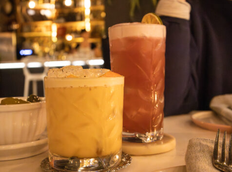two glasses of handcrafted cocktails in a dimly lit restaurant