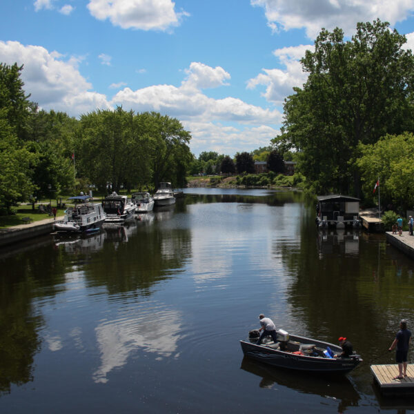 Image of a tree lined river with boats docked along side.