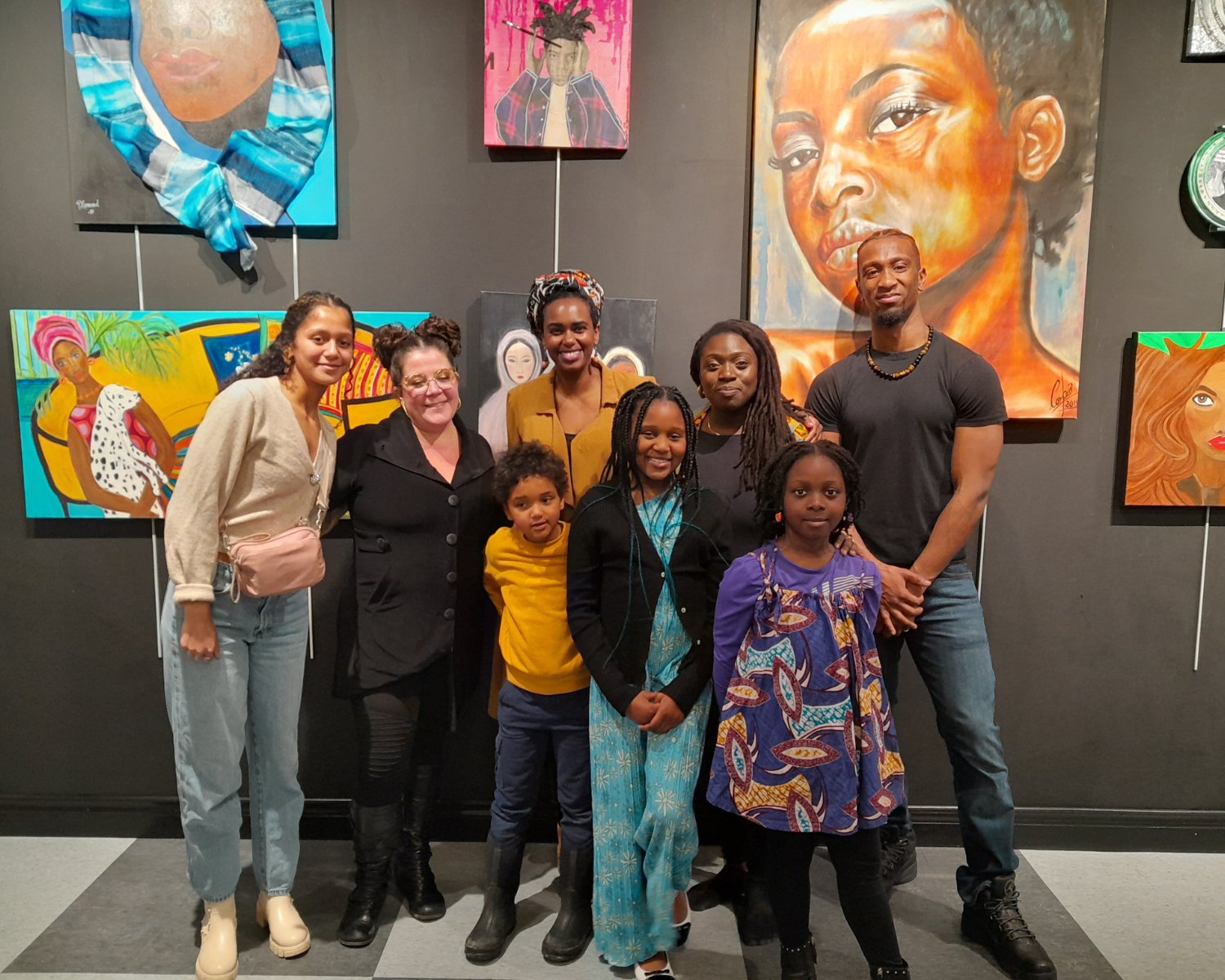 a group of adults and children posing in front of art in a gallery