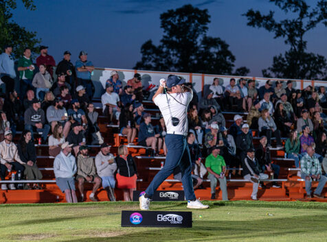 Photo of a golfer taking a swing in front of a crowd of people