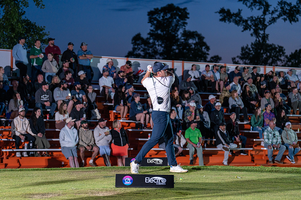 Photo of a golfer taking a swing in front of a crowd of people