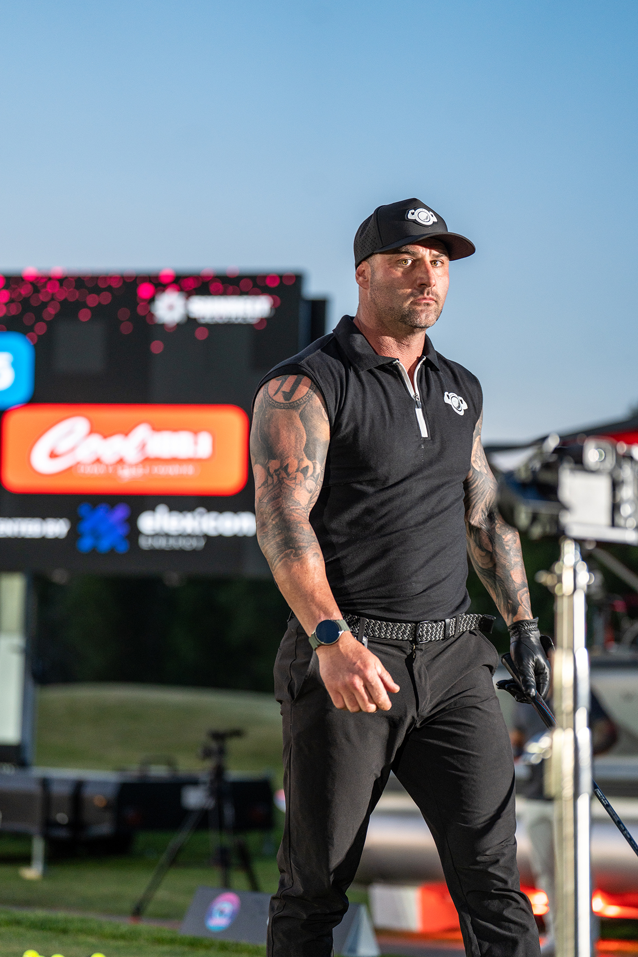 Photo of a golfer with big muscles and tattoos dressed in black