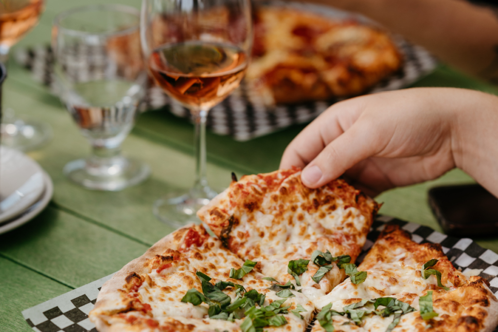 Image of a wood fired pizza and a glass of wine