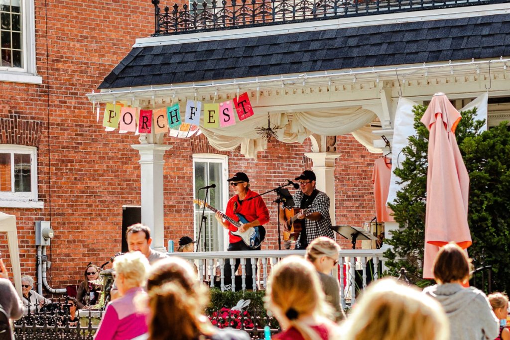 Image of a band playing on a porch with people watching from the street