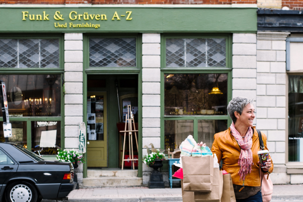Image of a person with shopping bags walking away from a vintage store front